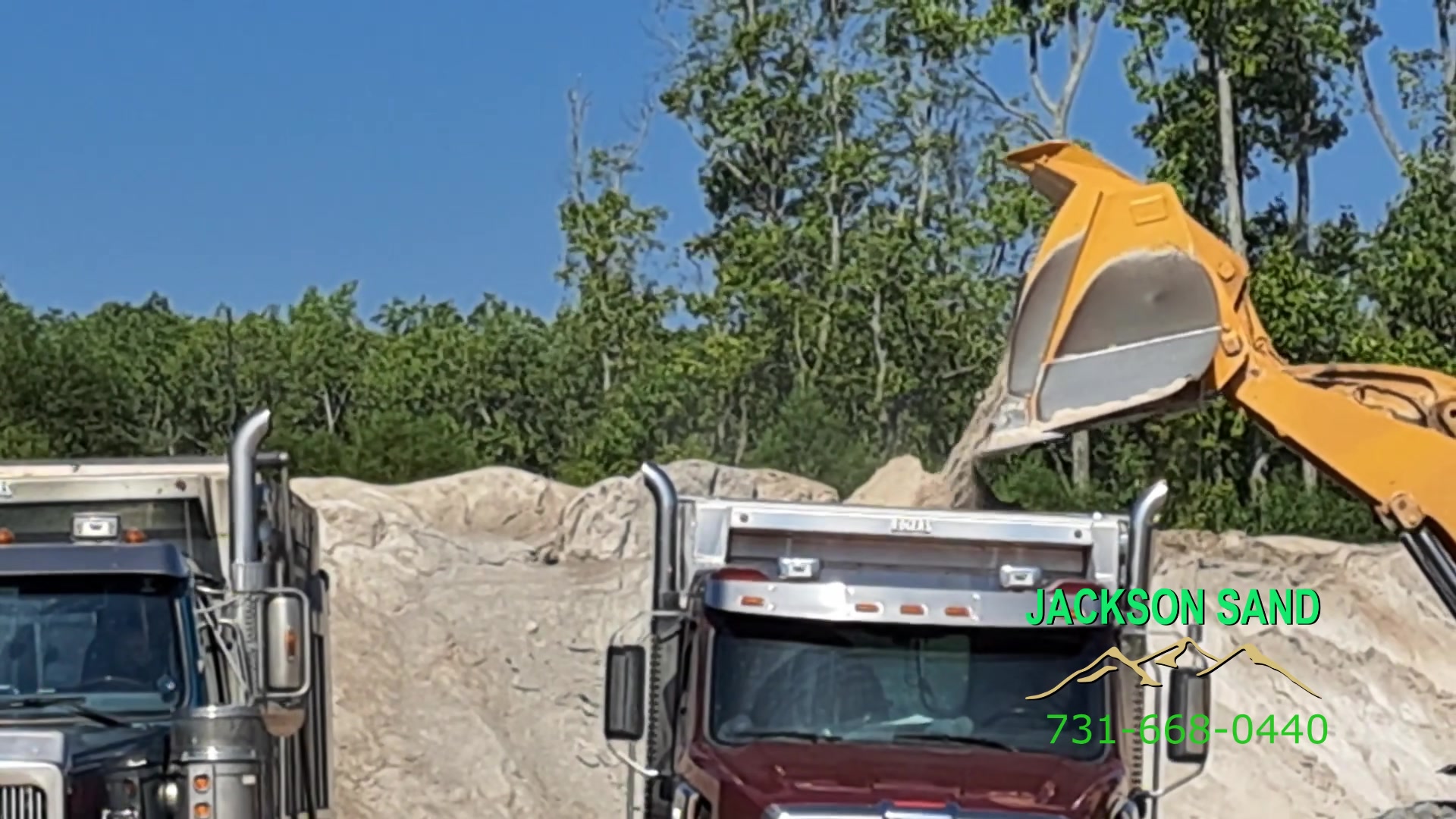 Wheel loader filling a Jackson Sand dump truck from a sand stockpile
